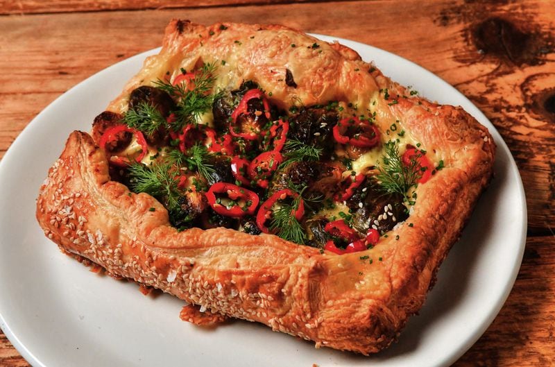This savory puff pastry galette, made by Two Urban Licks executive chef Shain Wancio, features cheese, fingerling potatoes and Brussels sprouts and can be topped with Pickled Fresno Peppers, dill sprigs and chopped chives. (Styling by chef Shain Wancio / Chris Hunt for the AJC)