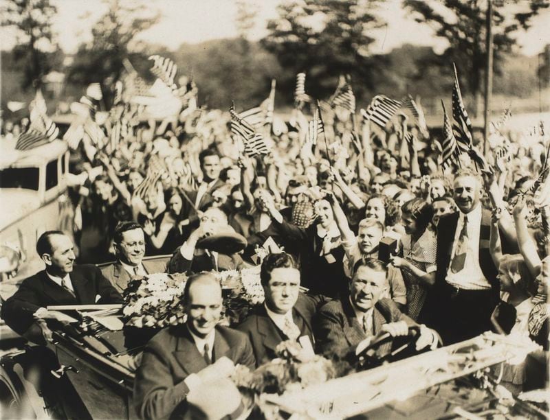 View of presidential candidate Franklin Delano Roosevelt (rear of car far right) waving to a crowd in Atlanta during a campaign visit to Georgia in October 1932. In his car, left to right, rear seat, are Georgia Senator Richard B. Russell, Jr.; Hugh Howell, chairman of the Georgia state democratic committee, and Roosevelt. In the front, left to right, are Mayor James Key, James Roosevelt, the nominees' son, and driver Alvin Belle Isle, an Atlanta businessman. Photo credit: Kenan Research Center at the Atlanta History Center.