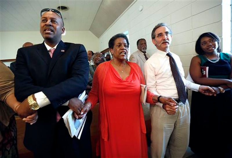 Meridian Mayor Percy Bland, left, holds hands with civil rights activist and widow of civil rights pioneer Medgar Evers, Myrlie Evers-Williams, and Dave Goodman, brother of slain civil rights worker Andrew Goodman during a ceremony at the Mt. Zion United Methodist Church in Philadelphia, Miss., Sunday, June 15, 2014. The commemorative service was for Goodman and two other civil rights workers killed in Neshoba County for their voter registration work among blacks in then segregationist Mississippi. (AP Photo/Rogelio V. Solis)