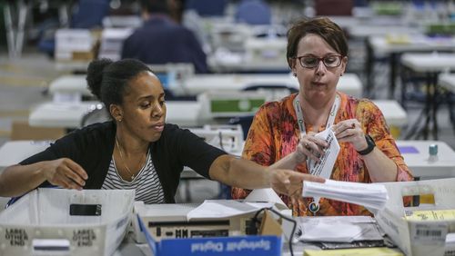 Elections Coordinator Shantell Black, left, and Elections Deputy Director Kristi Royston open and scan absentee ballots in November 2018 at the Voter Registration and Elections Office in Lawrenceville. JOHN SPINK/JSPINK@AJC.COM