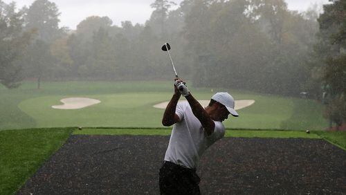 Defending champion Tiger Woods gets in a little wet Masters practice Wednesday at Augusta National, teeing off the par-3 4th hole.   “Curtis Compton / Curtis.Compton@ajc.com”