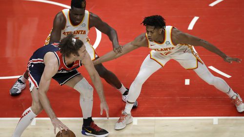 Clint Capela and De'Andre Hunter guard Wizards' Robin Lopez in the second half of an NBA basketball game Monday, May 10, 2021, in Atlanta.