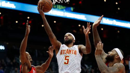 Atlanta Hawks guard Malcolm Delaney (5) goes between New Orleans Pelicans' Dante Cunningham (33) and DeMarcus Cousins (0) as he goes in for a shot during the first half of an NBA basketball game Wednesday, Jan. 17, 2018, in Atlanta. (AP Photo/John Bazemore)