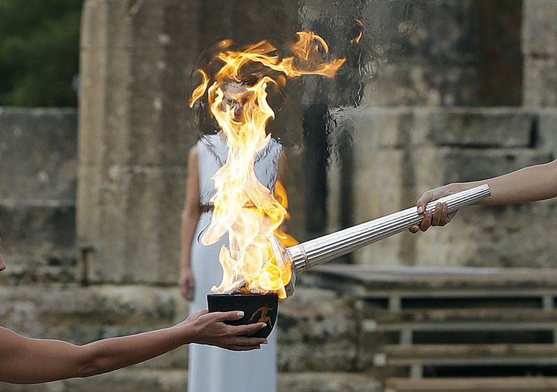 FILE - Actress Katerina Lehou, right, as high priestess, lights the torch during the lighting ceremony of the Olympic flame in Ancient Olympia, southwestern Greece, Oct. 24, 2017. On Tuesday, April 16, 2024 the flame for this summer's Paris Olympics will be lit and be carried through Greece for more than 5,000 kilometers (3,100 miles) before being handed over to French organizers at the Athens site of the first modern Olympics. (AP Photo/Thanassis Stavrakis, File)