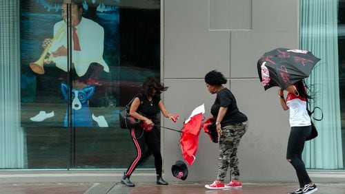 Three women contend with high winds while walking along Canal Street in New Orleans on Friday. The first major storm system expected to strike the U.S. this hurricane season strengthened into Tropical Storm Barry on Thursday, continuing to dump rain along already inundated parts of the Gulf Coast before its expected landfall on Saturday.