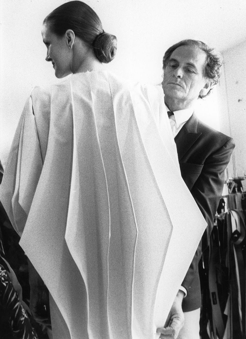 Designer Pierre Cardin is shown during a dress fitting in 1980. CONTRIBUTED BY ©ARCHIVES PIERRE CARDIN