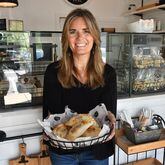 Belén de la Cruz holds a basket of empanadas in the ordering and dining area of her Johns Creek shop.