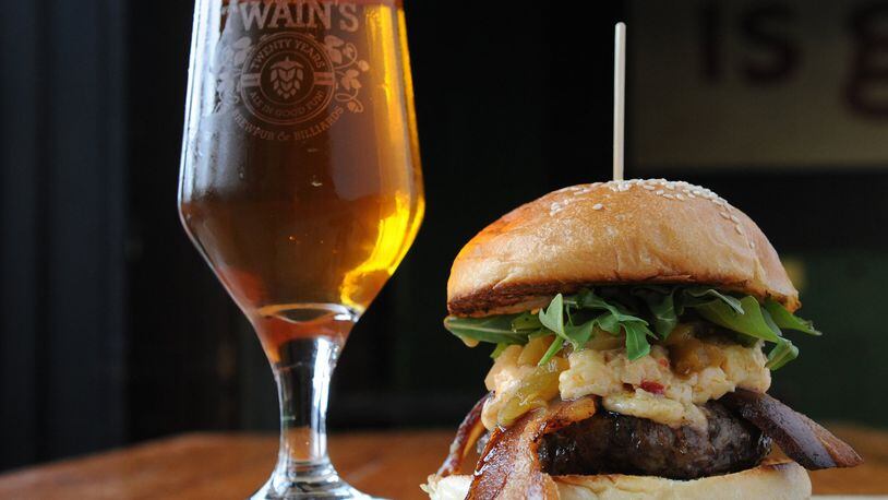 At Twain’s Brewpub & Billiards in Decatur, the Olivia Burger comes with pimento cheese, arugula, green tomato relish and bacon. It is served here with a pale ale. (Beckystein.com)
