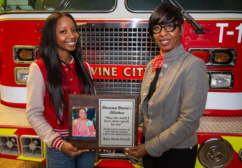 Karissa Ferrell-Hinkle (left) & Anissa Ferrell holds a plaque in honor of Rosa Marie Ferrell (Anissa's mother, Karissa's grandmother) who cooked for the annual community-wide Christmas Party at Fire Department's Station 16 in Vine City. The party had to be cancelled this year due to COVID-19. The station is also where the city's first African-American firefighters were employed. PHIL SKINNER FOR THE ATLANTA JOURNAL-CONSTITUTION.