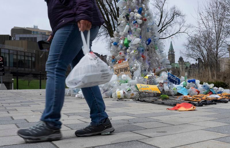 FILE - A person carries food in a plastic bag past an art installation outside the a United Nations conference on plastics on April 23, 2024, in Ottawa, Ontario. (Adrian Wyld/The Canadian Press via AP, File)