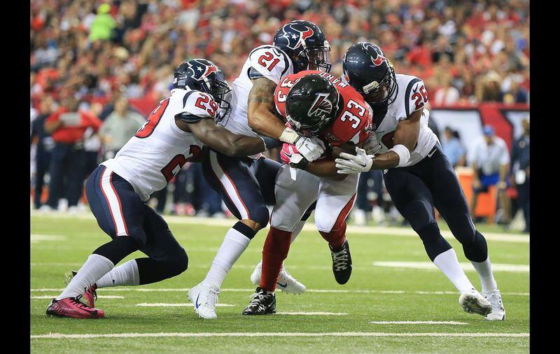 Falcons running back Terron Ward bulls his way through Texans defenders Andre Hall (from left), Darryl Morris, and Rahim Moore into the endzone for a touchdown and a 42-0 lead during the third quarter in a football game on Sunday, Oct. 4, 2015, in Atlanta. The Falcons beat the Texans 48-21. (Curtis Compton/ccompton@ajc.com)