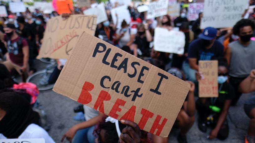 Protesters hold signs downtown on Monday. (Ben Gray for the Atlanta Journal Constitution)