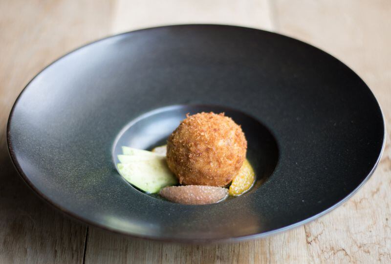 A first-course crab fritter is presented atop avocado and citrus. If you don’t order it, make sure someone at your table does. CONTRIBUTED BY HENRI HOLLIS