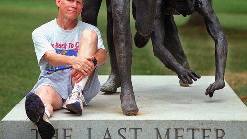 Dick Buerkle posed for this 1998 AJC photo after becoming the oldest winner of the masters division of the Peachtree Road Race. Buerkle sat at the base of "The Last Meter" sculpture in Piedmont Park, which depicts the conclusion of the final of the 5,000 meters at the 1976 Olympics, a race that he qualified for but did not reach the finals. (AJC file photo by Alicia Hansen)