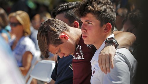 Ryan Schroy, 15, center, bows his head in prayer as he embraces Dylan O'Neill, 15, right, both students at Marjory Stoneman Douglas High School, during a vigil at the Parkland Baptist Church, for the victims of the Wednesday shooting at the high school, in Parkland, Fla., Thursday, Feb. 15, 2018. Nikolas Cruz, a former student, was charged with 17 counts of premeditated murder on Thursday.