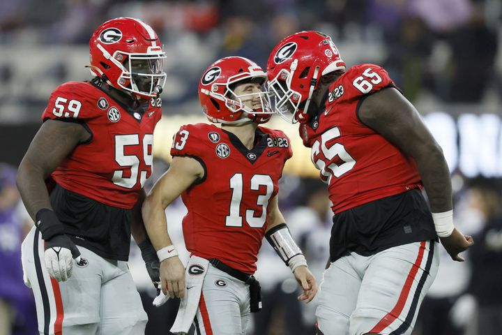 Georgia Bulldogs quarterback Stetson Bennett (13) celebrates a score against the TCU Horned Frogs with offensive linemen Broderick Jones (59) and Amarius Mims (65) during the second half of the College Football Playoff National Championship at SoFi Stadium in Los Angeles on Monday, January 9, 2023. Georgia won 65-7 and secured a back-to-back championship. (Jason Getz / Jason.Getz@ajc.com)