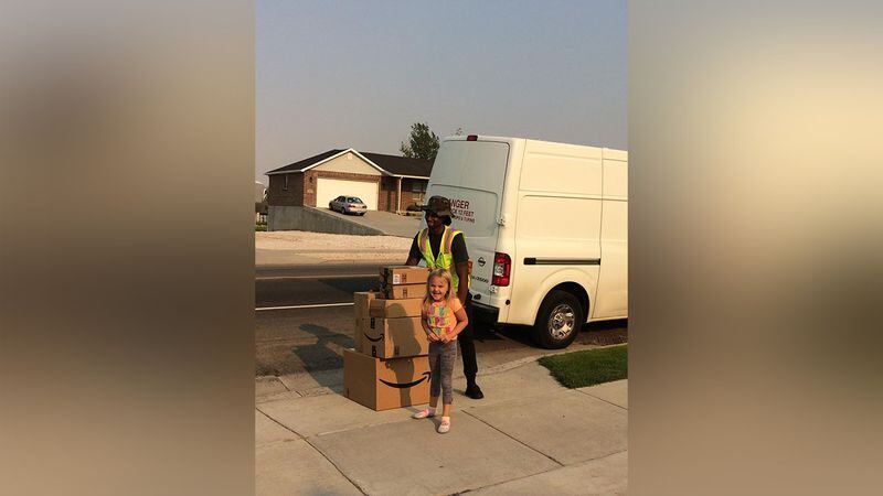 Katelyn Lunt, 6, poses with the delivery driver after surprising her family with a $350 toy shopping spree using her mom's Amazon account.