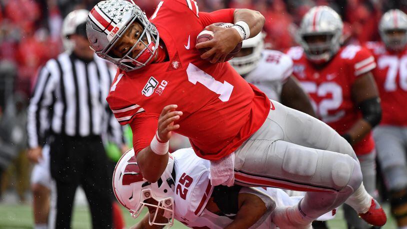 Ohio State quarterback Justin Fields dives over Wisconsin's Eric Burrell and into the end zone on a 10-yard touchdown run against the Badgers Saturday.  (Photo by Jamie Sabau/Getty Images)