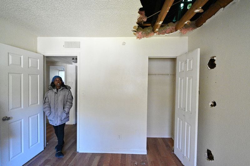 Pavilion Place resident Danielle Russell points out fire and water damage inside a vacant unit across the hall from her apartment. She suspected that squatters and other intruders had begun to stay there after a Sept. 23 fire. (Hyosub Shin / hyosub.shin@ajc.com)