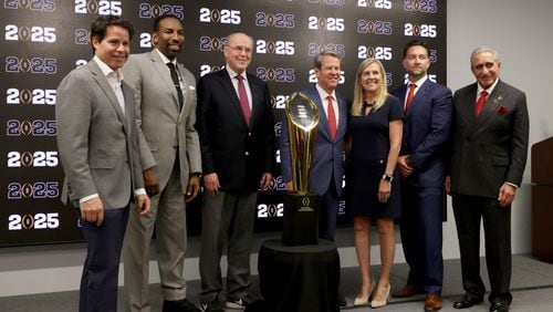 081622 Atlanta, Ga.: From left to right; Atlanta Sports Council president Dan Corso, Mayor Andre Dickens, College Football Playoff executive director Bill Hancock, Governor Brian and Marty Kemp, SVP Chief Revenue Officer Tim Zulawski, and Atlanta Falcons owner Arthur Blank pose for a photograph in front of the CFP National Championship trophy at Mercedes-Benz Stadium, Tuesday, August 16, 2022, in Atlanta. The CFP National Championship game will be played at Mercedes-Benz Stadium in 2025. (Jason Getz / Jason.Getz@ajc.com)