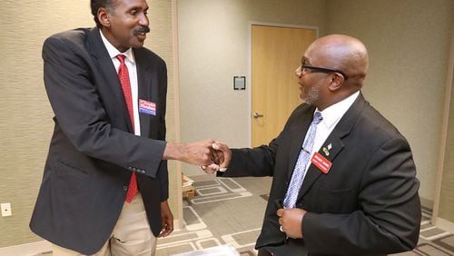 Candidates for the DeKalb County Commission Randal Mangham (left) and Greg Adams shake hands as they arrive for a debate at the Tucker-Reid H. Cofer Library on Tuesday. Curtis Compton/ccompton@ajc.com