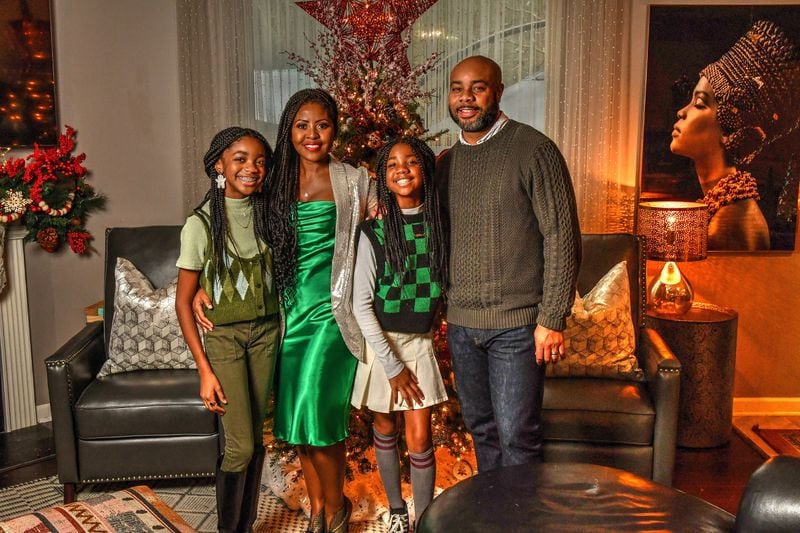 Chef Razia Sabour (second from left) is happy to be home for the holidays with her family, especially after being gone to film “The Great Soul Food Cook-Off,” a new cooking competition on Discovery+. She's shown with daughters Layla Burton (left, age 13) and Caden Burton (third from left, age 10) and husband Michael Burton. (Chris Hunt for the AJC)
