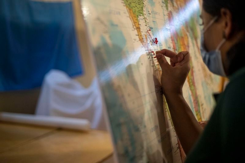 After being driven to the Casa Alterna hospitality residence, an immigrant woman uses a pin to locate the country from which she traveled on a map at the organization's residence in Decatur, Friday, Aug. 20, 2021. (Alyssa Pointer/Atlanta Journal Constitution)