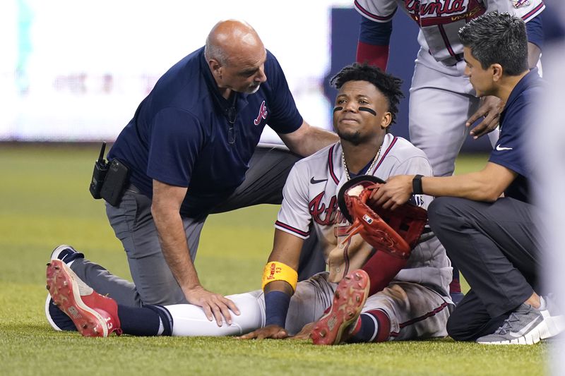 Braves right fielder Ronald Acuna sits injured on the field after trying to make a catch on an inside the park home run hit by Miami Marlins' Jazz Chisholm Jr. during the fifth inning Saturday, July 10, 2021, in Miami. (Lynne Sladky/AP)