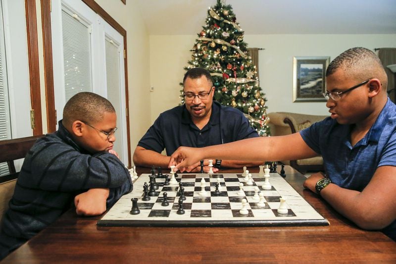 Even before Corey McDaniel lost his wife, he says, he and his sons spent a lot of time together playing chess, watching movies, attending church and enjoying the outdoors with their Boy Scout troop. Here, he’s playing chess with his sons Corey Jr. (right), 14, and Christian, 11, at their Stone Mountain home. ALYSSA POINTER/ALYSSA.POINTER@AJC.COM