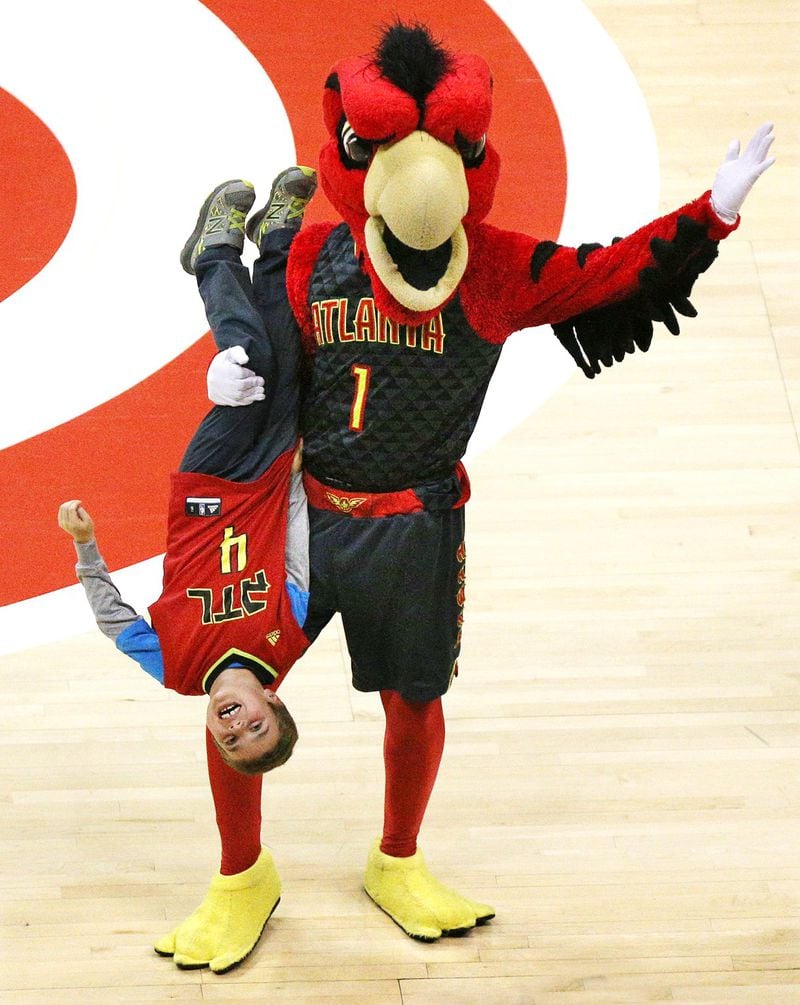 Harry the Hawk entertains the audience at the expense of a youngster with a courtside seat while the Atlanta Hawks play the Utah Jazz. CURTIS COMPTON / CCOMPTON@AJC.COM