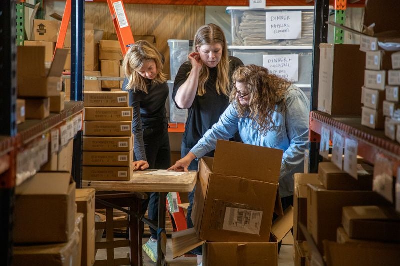 Relish owners Susan Peterson (L) and Cabell Sweeney (R), along with employee Chelsey Riley (C), look over an order they are preparing to ship at their Rome warehouse Tuesday, April 12, 2022 (Steve Schaefer / steve.schaefer@ajc.com)