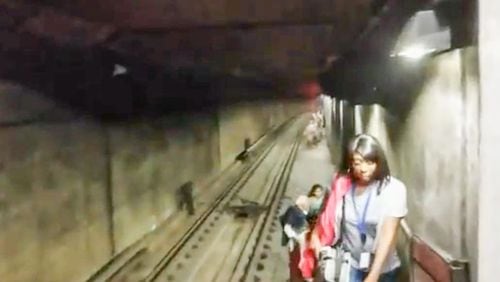 MARTA passengers walk through a tunnel after climbing out of a stalled train car near the Arts Center station on Wednesday night.