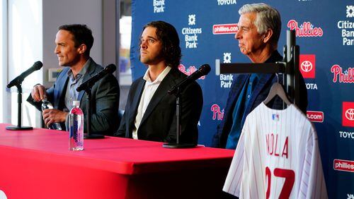 Philadelphia Phillies baseball team pitcher Aaron Nola, center, takes questions from the media after signing a seven-year contract, with President of Baseball Operations David Dombrowski, right, and Vice President and General Manager Sam Fuld, left, Monday, Nov. 20, 2023, in Philadelphia. (AP Photo/Chris Szagola)