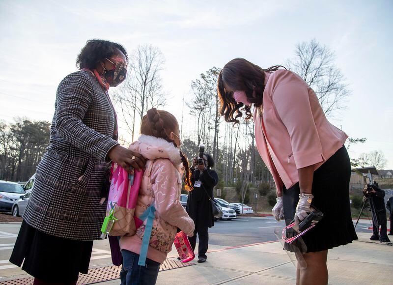  John R. Lewis Elementary School principal LaShawn McMillan, right, greets students as their dropped off for the first day of in-person learning at John R. Lewis Elementary School in Brookhaven, Tuesday, March 9, 2021. (Alyssa Pointer / Alyssa.Pointer@ajc.com)