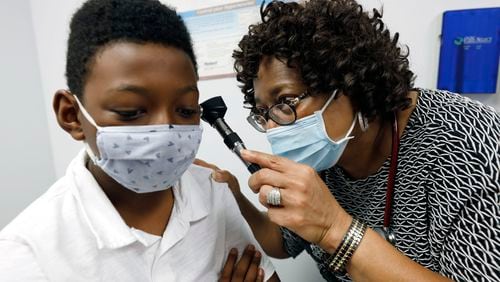Dr. Janice Bacon, a primary care physician with Central Mississippi Health Services, gives Jeremiah Young, 11, a back-to-school physical, at the Community Health Care Center on the Tougaloo College campus. As a Black primary care physician, Bacon has created a safe space for her Black patients during the coronavirus pandemic. (AP Photo/Rogelio V. Solis)