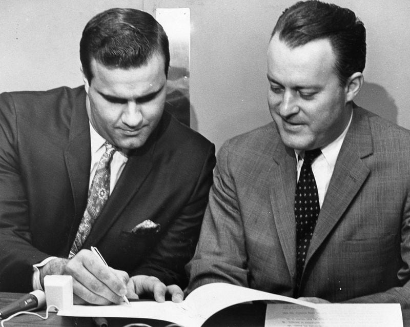 In 1967, Braves owner Bill Bartholomay (right) watches catcher Joe Torre sign a new contract, which made Torre the highest paid catcher in baseball at the time at $65,000 a year.