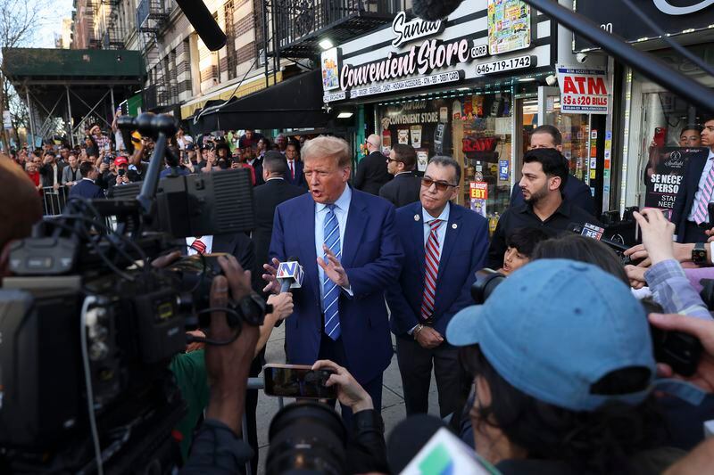 Former president Donald Trump, talks to members of the media while visiting a bodega, Tuesday, April 16, 2024, who's owner was attacked last year in New York. Fresh from a Manhattan courtroom, Donald Trump visited a New York bodega where a man was stabbed to death, a stark pivot for the former president as he juggles being a criminal defendant and the Republican challenger intent on blaming President Joe Biden for crime. Alba's attorney, Rich Cardinale, second from left, and Fransisco Marte, president of the Bodega Association, looked on. (AP Photo/Yuki Iwamura)