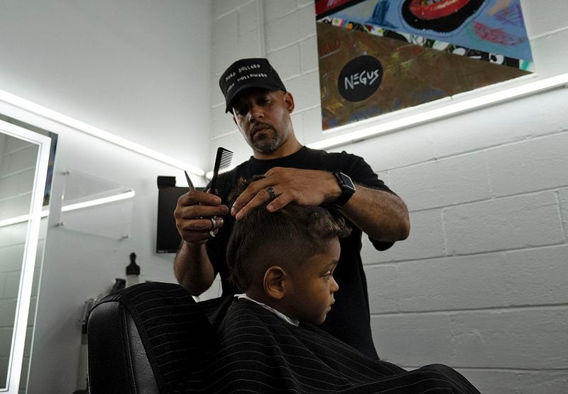 July 13, 2020, Atlanta — Samuel Glickman, owner of Privado Barbershop in Vine City, cuts the hair of his toddler client. Glickman opened his shop up for “The Confess Project,” an organization that enlists barbershops like Privado to double as mental health centers, where Black men can comfortably talk about their issues. (RYON HORNE/RHORNE@AJC.COM)