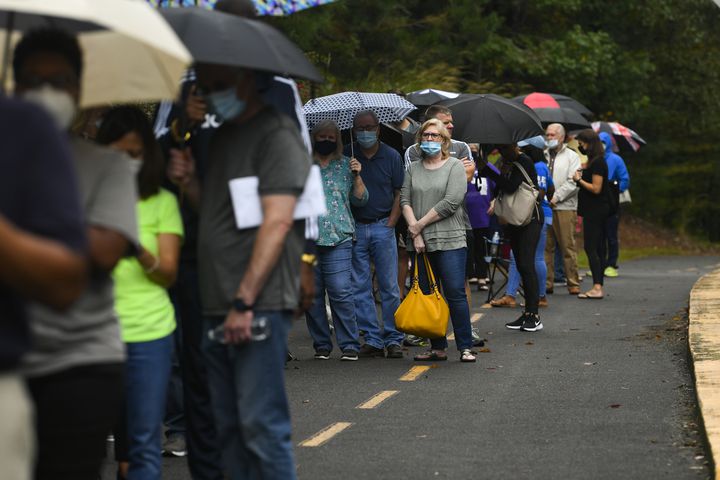 A woman who prefers to stay unidentified stands near the back of a voting line with others that has an estimated 3 hour wait, as the first day of early voting is shown underway on Monday, Oct. 12, 2020, at the George Pierce Park  in Suwanee, Ga. JOHN AMIS FOR THE ATLANTA JOURNAL- CONSTITUTION