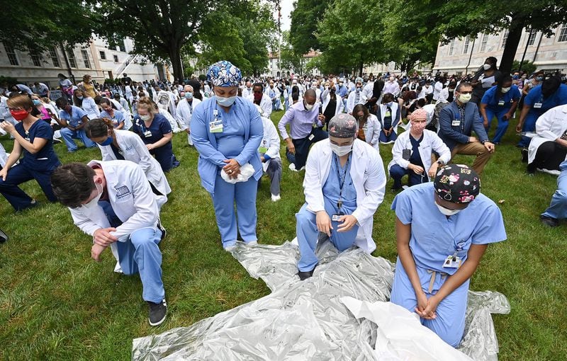 June 5, 2020 Decatur - Foreground from left, Max Schubert, MD, Micky Davis (Nurse Practitioner), Thien Le, MD, and Yvonne Little, MD, take a knee for eight minutes and 46 seconds in memory of George Floyd "and countless others," in a demonstration they call White Coats for Black Lives at Emory University Quadrangle on Emory University campus in Decatur on Friday, June 5, 2020. Doctors these days are finding themselves at the intersection of America's race debate: giving advice to protestors on how to protect their eyes from tear gas and speaking their frustration at seeing people of color disproportionately sickened by COVID-19. On Friday at 1pm, a group organized by Emory med students is taking a knee at Emory University for eight minutes and 46 seconds in memory of George Floyd "and countless others," in a demonstration they call White Coats for Black Lives. (Hyosub Shin / Hyosub.Shin@ajc.com)