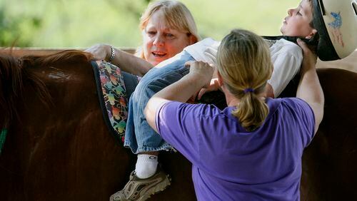 In this June 26, 2008 photo, Cole Simonds, 5 1/2, of Lilburn, rides the horse flat on his back with help from volunteer Terry Allen, left, of Lawrenceville, and Dr. Marilyn Peterson of Snellville, during a therapeutic ride at Parkwood Farms Therapy Center in Snellville. The center provides therapy for children with special needs including autism, Downs' Syndrome, Cerebral Palsy, emotional problems and learning disabilities.