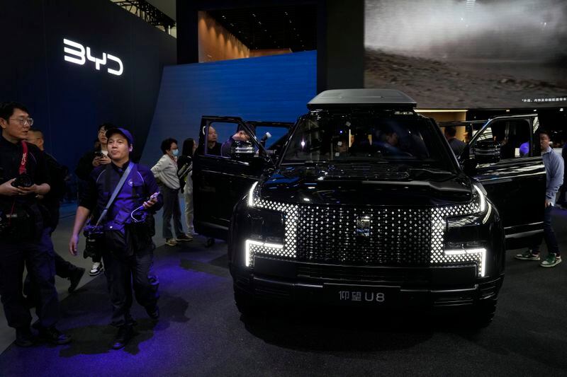 Attendees walk near the U8 from Yangwang during Auto China 2024 in Beijing, Thursday, April 25, 2024. China's vision of the future of the automobile — electrified and digitally connected — is on display at the ongoing Beijing auto show. (AP Photo/Ng Han Guan)