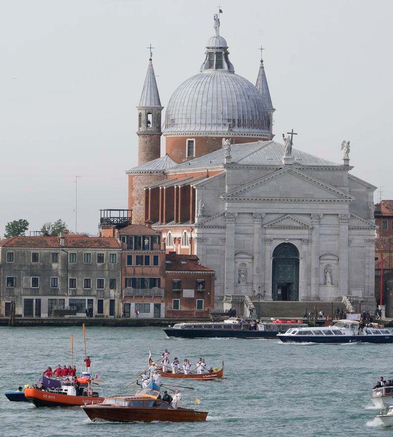 ALTERNATIVE CROP OF ALT105 - Pope Francis, foreground, is greeted by Gondoliers upon his arrival in Venice, Italy, Sunday, April 28, 2024. The Pontiff arrived for his first-ever visit to the lagoon town including the Vatican pavilion at the 60th Biennal of Arts. In background is the Church of the Most Holy Redeemer. (AP Photo/Alessandra Tarantino)