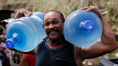 A man carries two water jugs filled with water near San Juan.