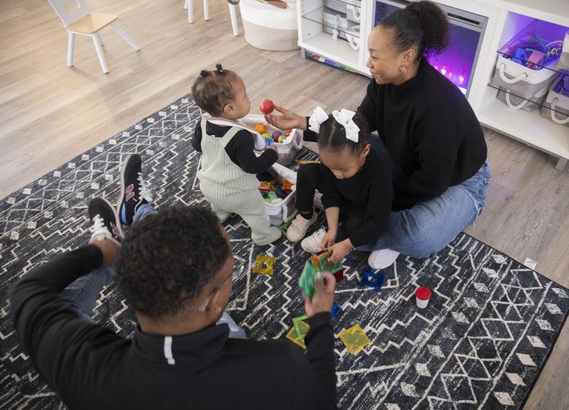 Kenneth Rioland, left, and Daizha Rioland play with their daughters, 9-month-old Izabella and Alani, 2, at their home on Saturday, Feb. 17, 2024, in Dallas. The family has struggled to find quality child care for their first daughter. (Juan Figueroa/The Dallas Morning News via AP)