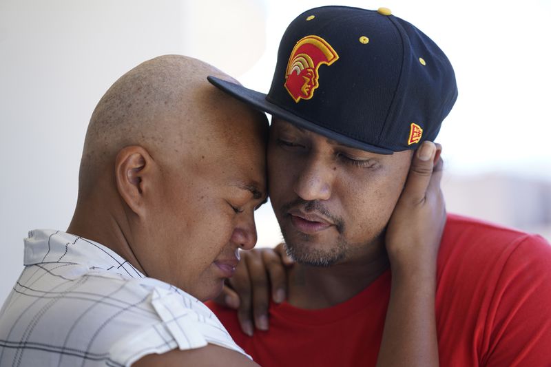 FILE - JP Mayoga, right, a chef at the Westin Maui, Kaanapali, and his wife, Makalea Ahhee, hug on their balcony at the hotel and resort, Sunday, Aug. 13, 2023, near Lahaina, Hawaii. About 200 employees were living there with their families. (AP Photo/Rick Bowmer, File)