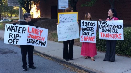 DeKalb County residents protest high water bills outside the county government center on Tuesday, Oct. 11, 2016. From left: Hope Lusignan, Anita Connor, Judy Knight and Commissioner Nancy Jester hold signs calling for the county government to fix the problem. MARK NIESSE / MARK.NIESSE@AJC.COM