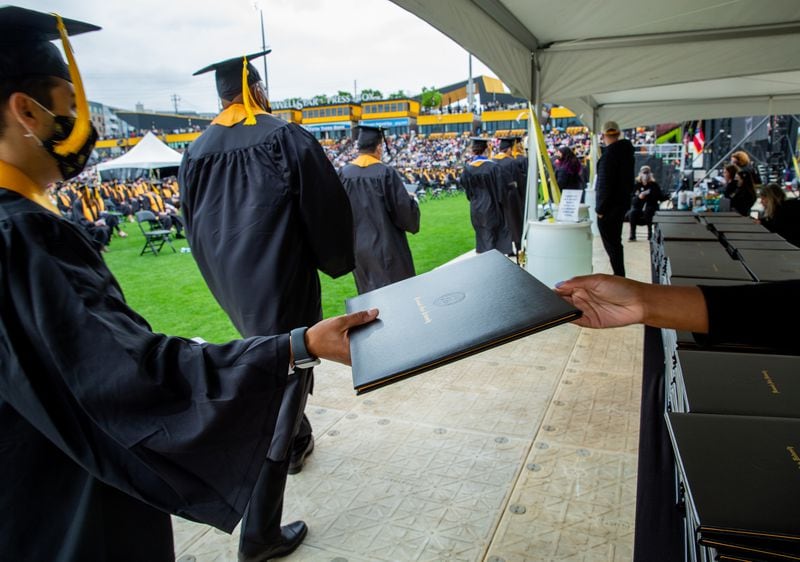 Kennesaw State University holds graduation Wednesday May 12, 2021 at the college’s stadium.  Graduates are handed diplomas during the ceremony but will receive their specific diploma after graduation.   (Jenni Girtman for The Atlanta Journal Constitution)