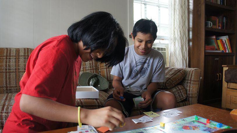 Javy (left) and Teo McGinnis, 12-year-old twin sons of El Refugio volunteer Marilyn McGinnis, play Monopoly in the living room at El Refugio. CONTRIBUTED BY STELL SIMONTON