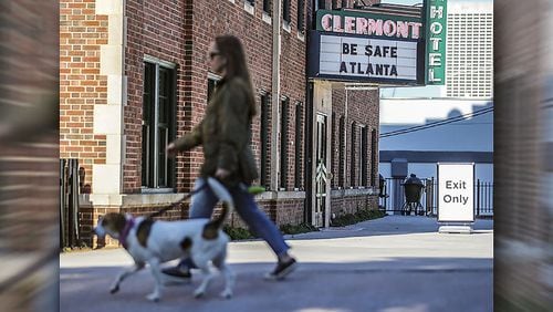 Allegra Stanek walks her dog Memphis past the sign reading, "Be safe Atlanta," at Hotel Clermont on Ponce de Leon Avenue in northeast Atlanta.